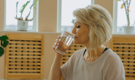 middle aged woman drinking a glass of water